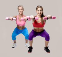 Two beautiful young woman doing fitness exercise with dumbbells